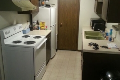 A kitchen with white appliances and brown cabinets.