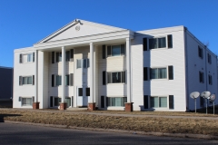 A large white building with two windows and shutters.