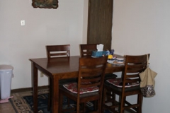 A dining room table with four chairs and a rug.