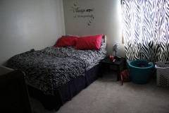 A bedroom with a bed, nightstand and window.