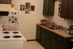 A kitchen with brown cabinets and white appliances.