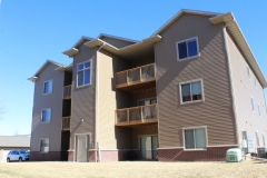 A brown building with balconies and a sandy beach.
