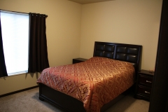 A bed room with a neatly made bed and a table