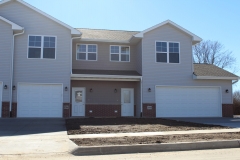 A row of three story houses with garage doors.