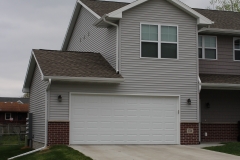 A house with two garage doors and a brick driveway.