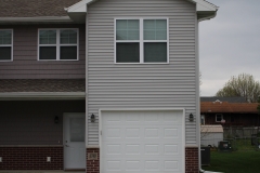 A house with two windows and a garage door.