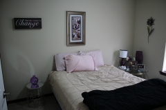 A bedroom with a bed, nightstand and picture on the wall.