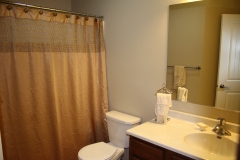 A bathroom with a toilet, sink and mirror.